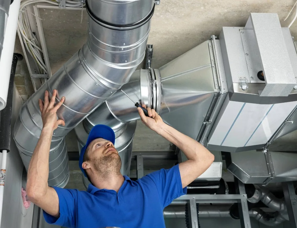 An engineer wearing blue repairing ventilation.