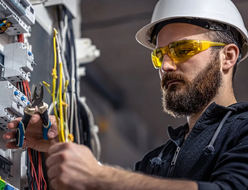 An engineer in protective gear cuts a cable.