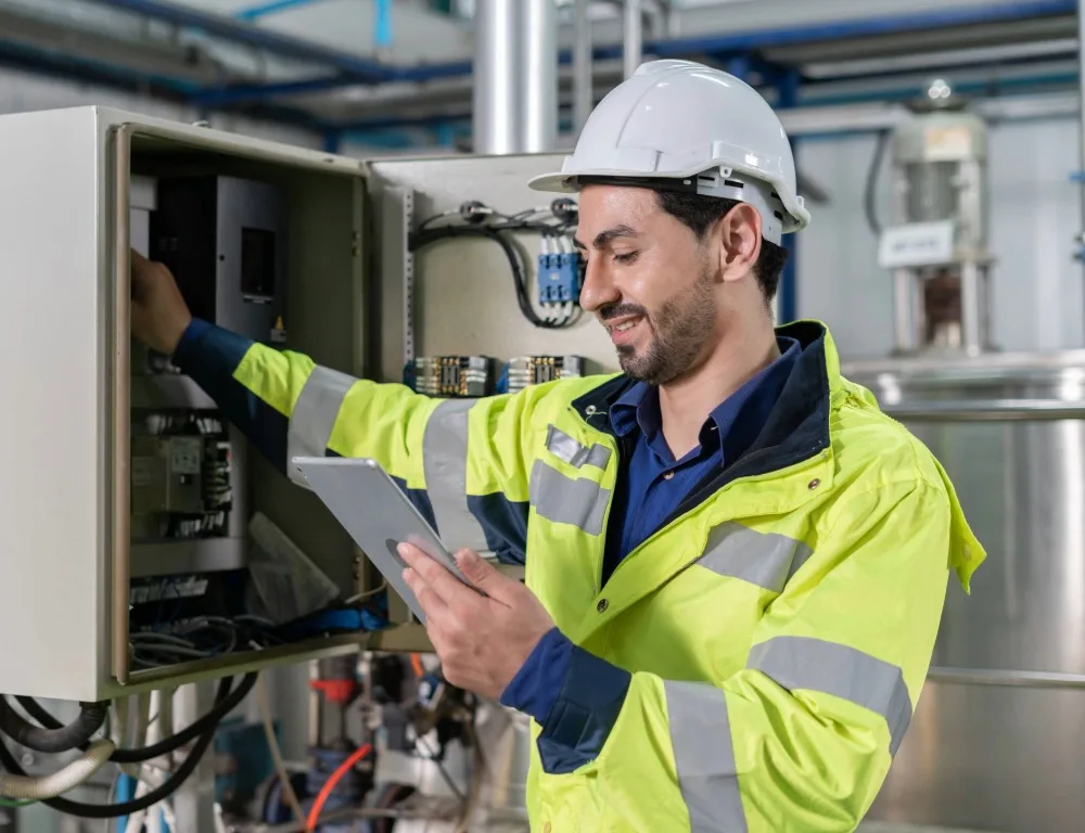 A man in protective gear inspecting an electrical installation.